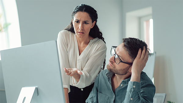 Business owner and employee reacting with concern while reviewing health insurance costs on a computer